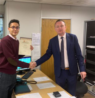 Ashley Waters (l) of Edmundson Electrical Blackfriars receives his Distinction certificate from manager Paul Conneely. (March 2019)