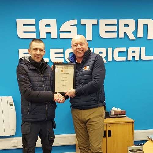 Joe Horgan, Manager at Eastern Electrical (Cork branch) handing  Criostoir Edwards his Product Knowledge Module: Introduction to the Principles of Electricity.   Criostoir achieved a Distinction. 