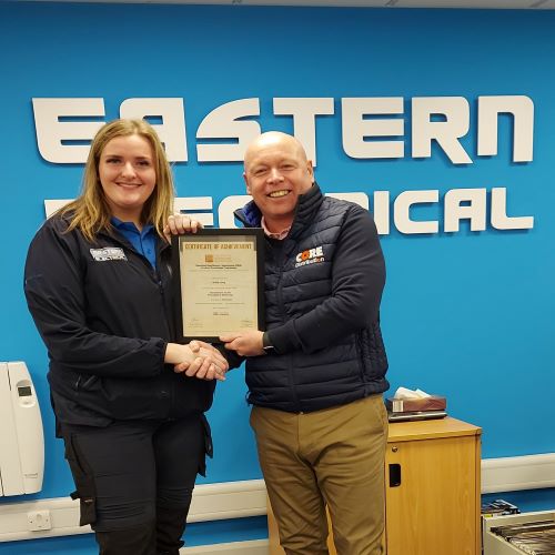 Joe Horgan, Manager at Eastern Electrical (Cork branch) handing Holly Long her  Product Knowledge Module: Introduction to the Principles of Electricity.  Holly achieved a Distinction. 
